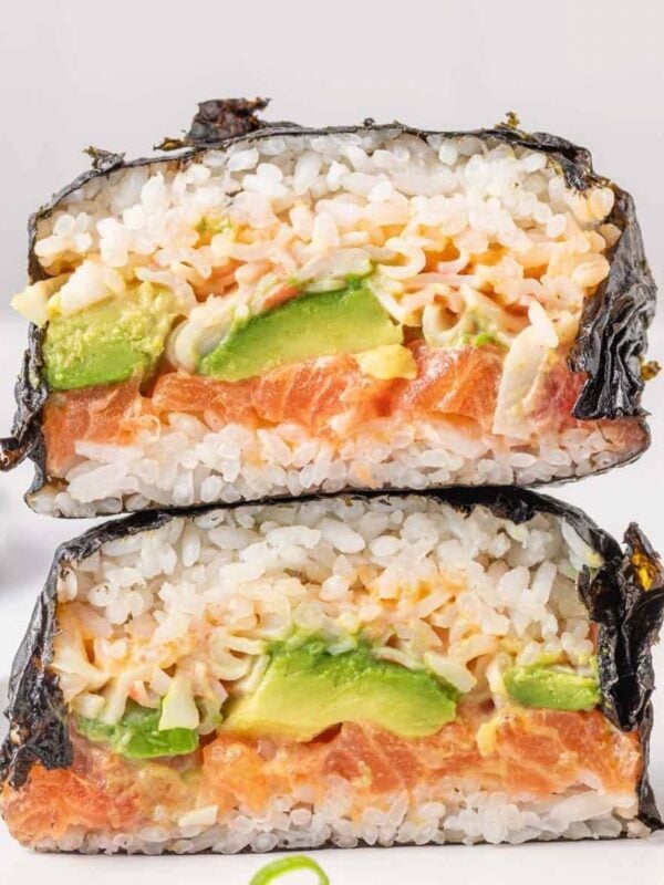 Sliced sushi burger showing layers of salmon, avocado, imitation crab, rice, and nori.