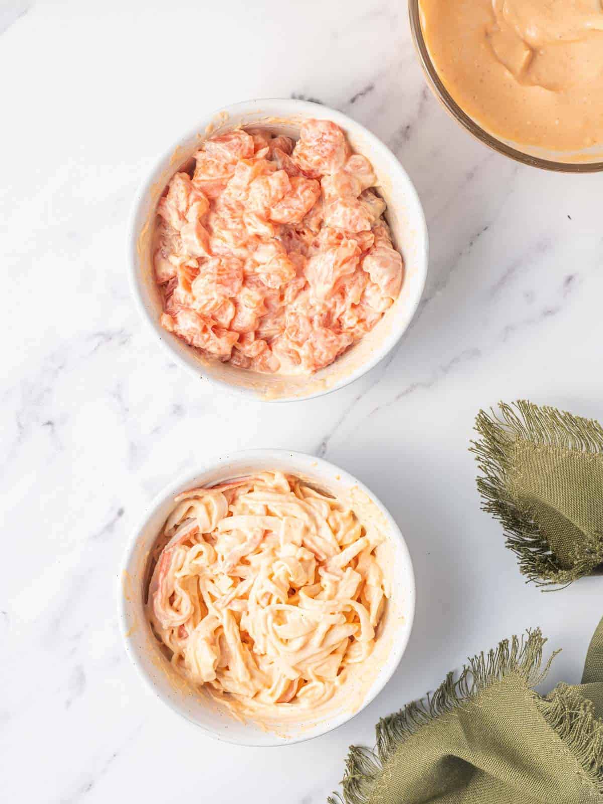 Separate bowls of salmon and imitation crab mixed with spicy mayo.