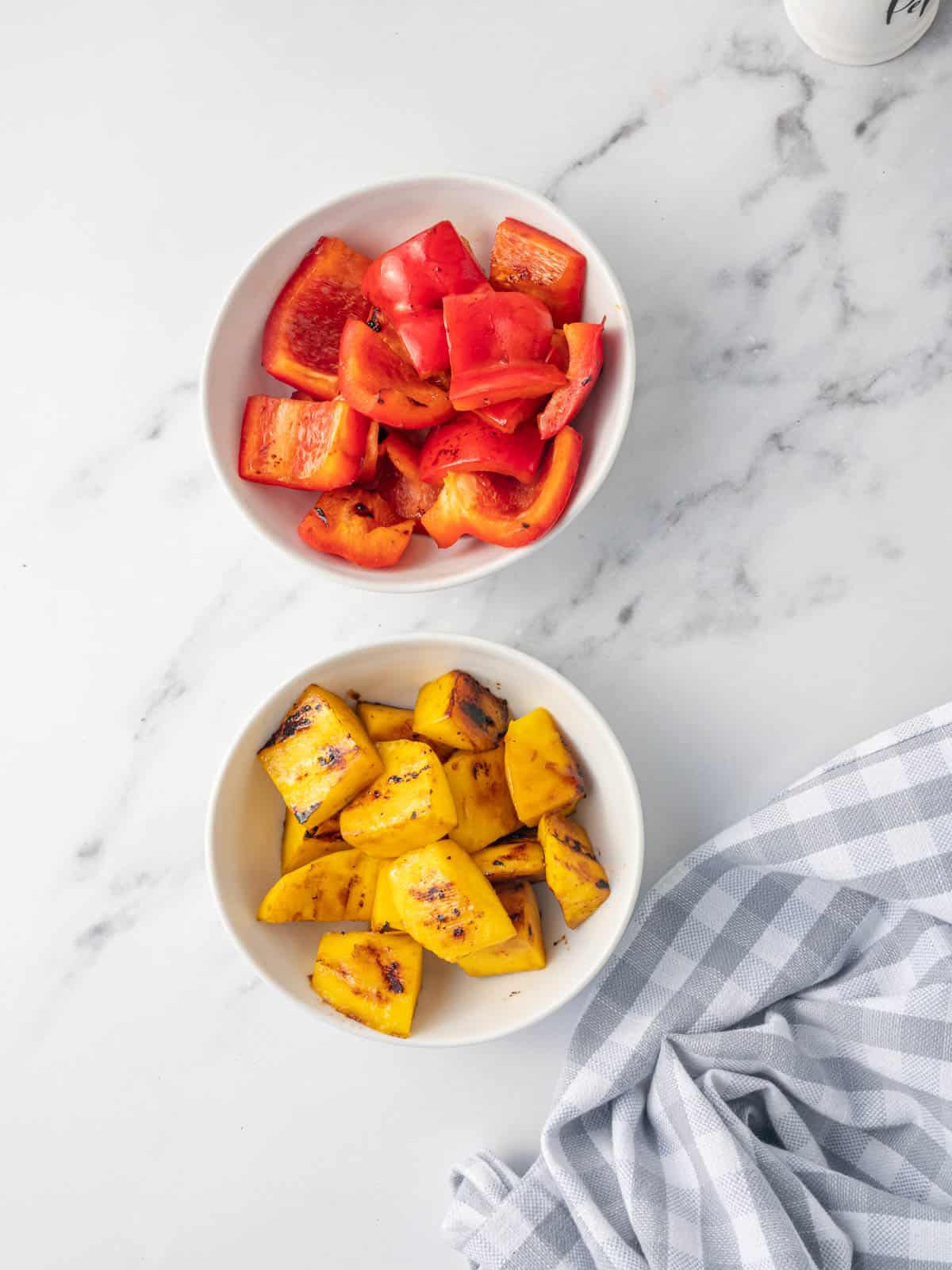 Bowls of sauteed red bell peppers and mango chunks.