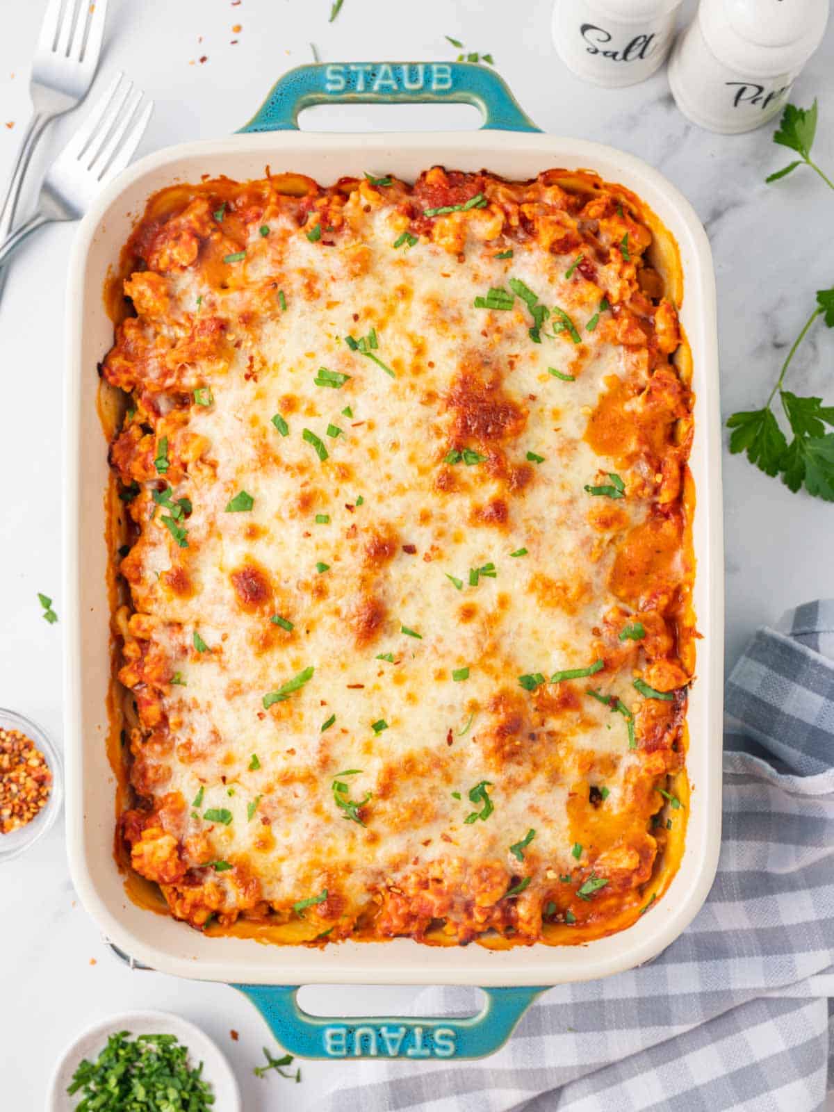 Baked alfredo pasta topped with cheese in a casserole dish.