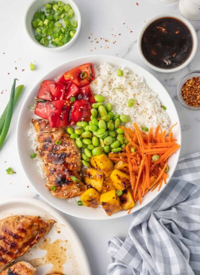 A teriyaki chicken rice bowl with condiments on the side.