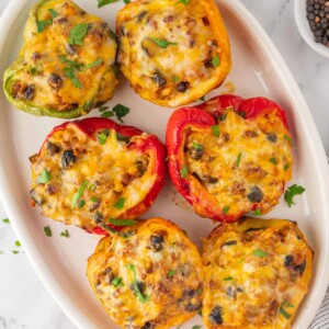 A plate with six stuffed peppers.