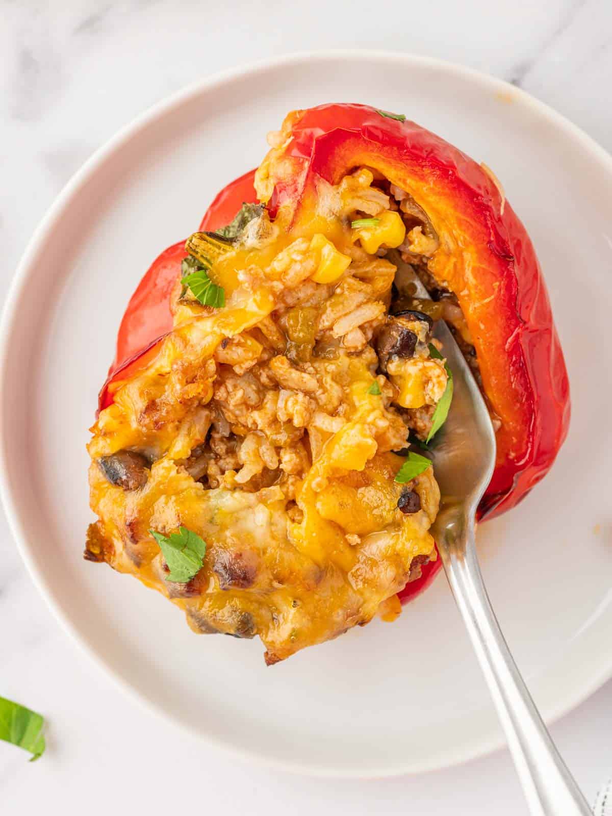 A fork scoops filling out of a stuffed pepper.
