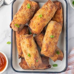 A platter of crispy homemade spring rolls with dipping sauce.