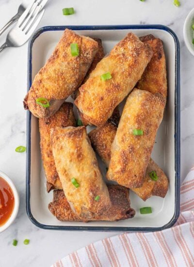 A platter of crispy homemade spring rolls with dipping sauce.