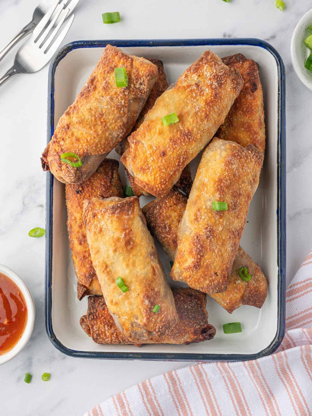 A platter of crispy homemade spring rolls with dipping sauce.