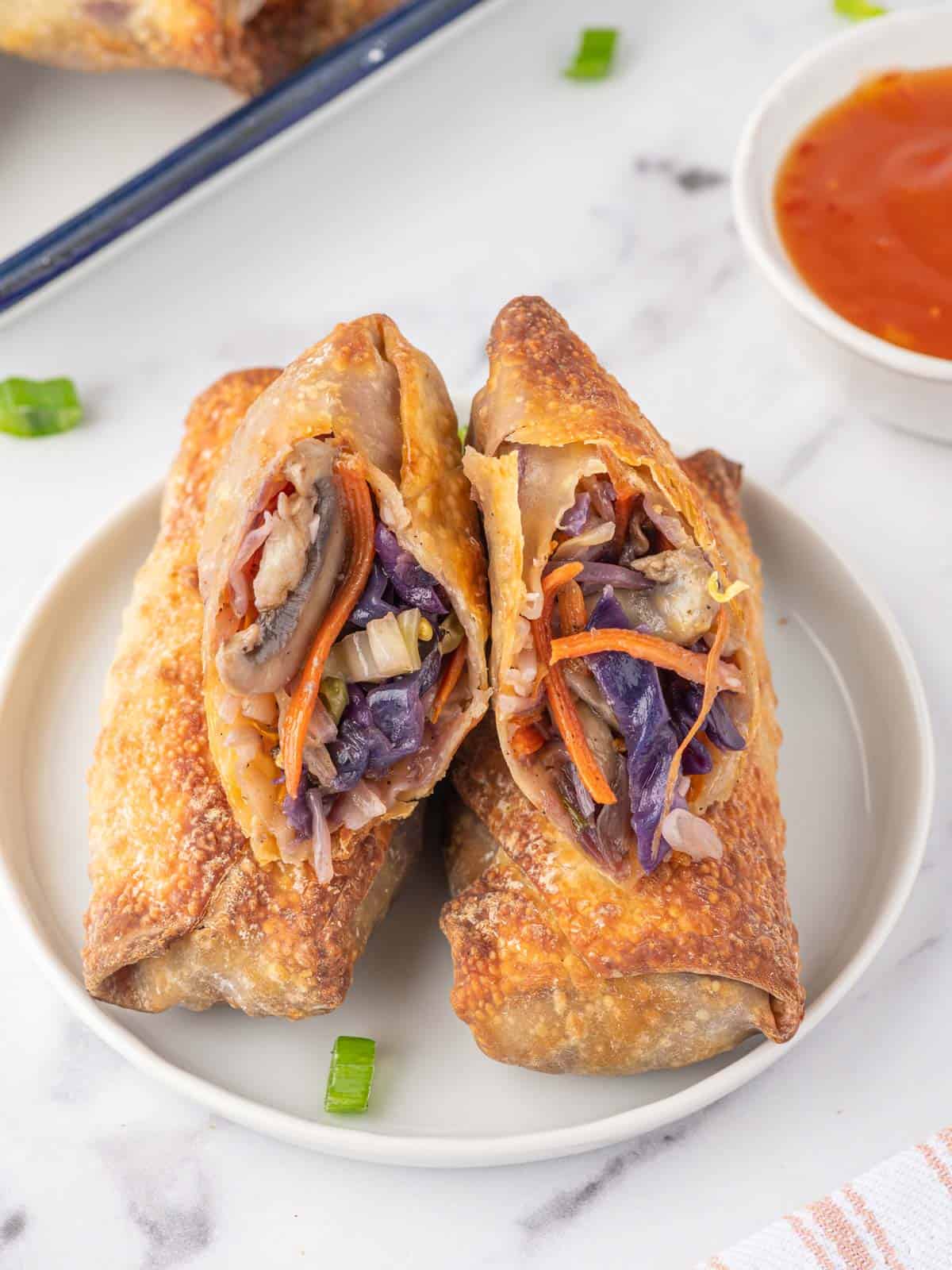 A veggie filled spring roll rests on a plate.