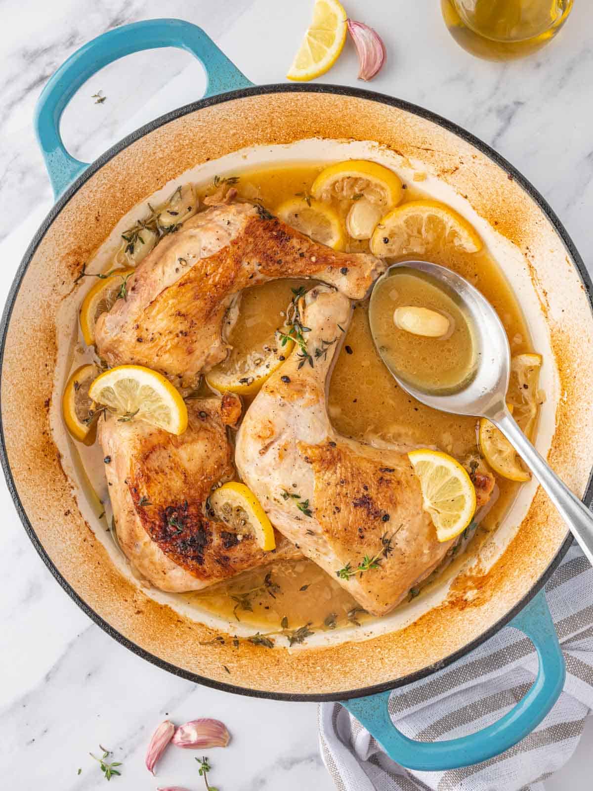 A spoon bastes braised chicken quarters.