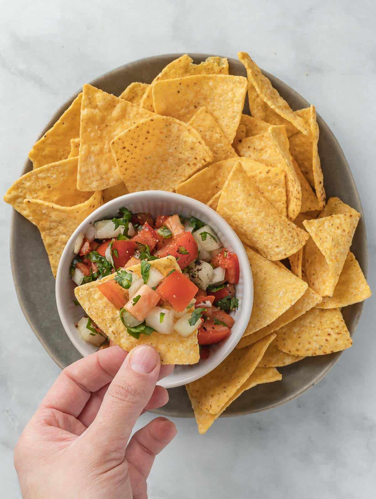 hand scooping pico de gallo.