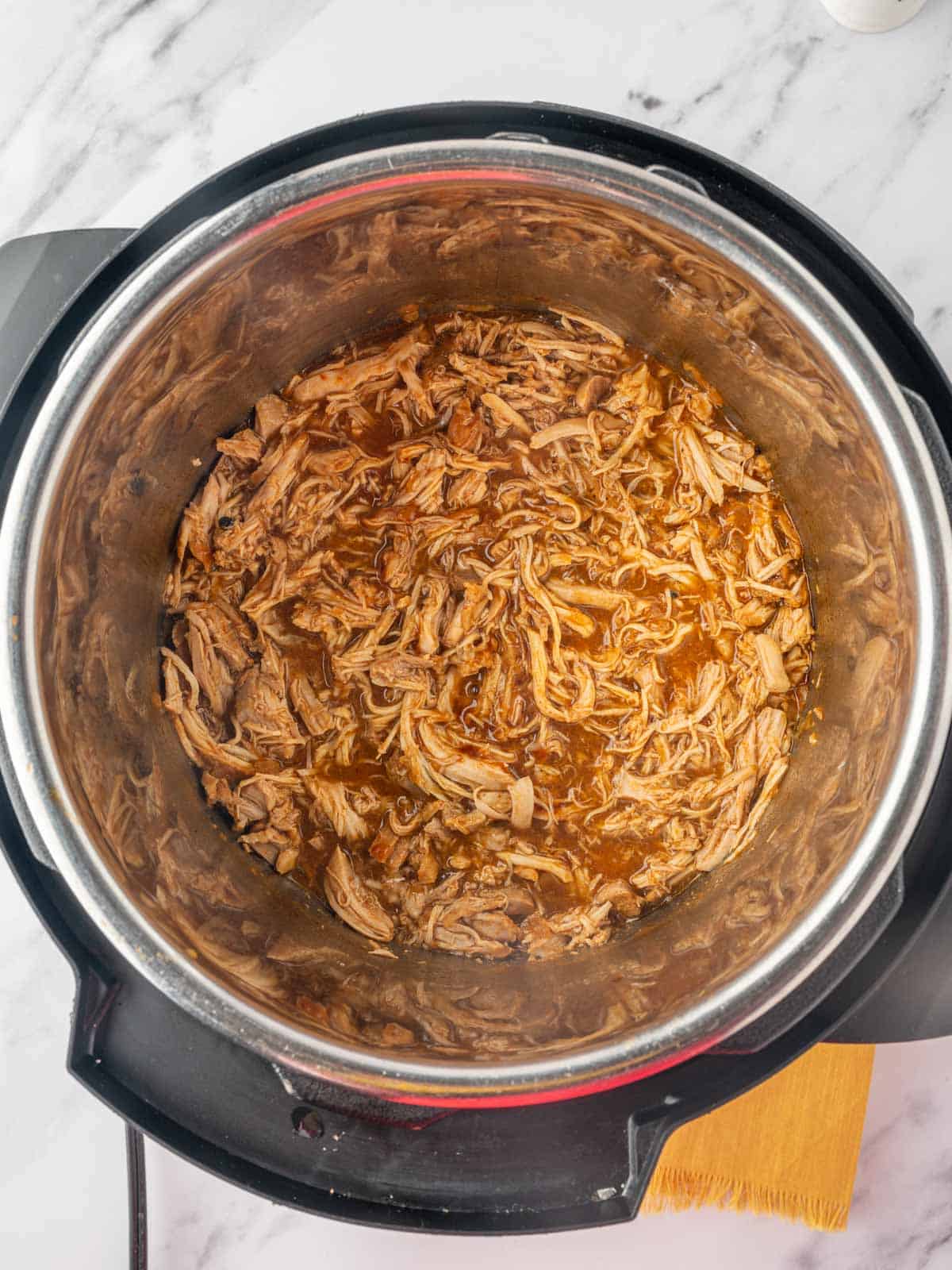 Shredded chicken with bbq sauce in the bottom of an instant pot.