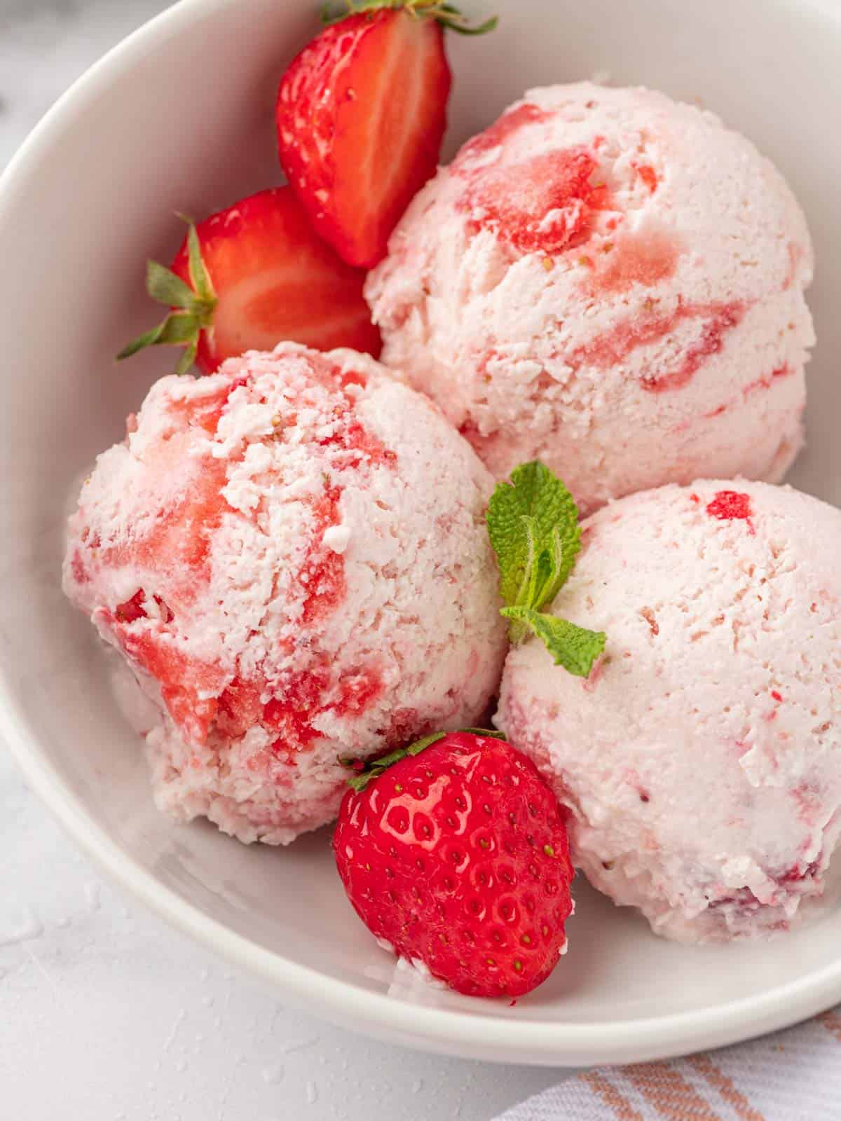 Scoops of strawberry ice cream in a bowl.