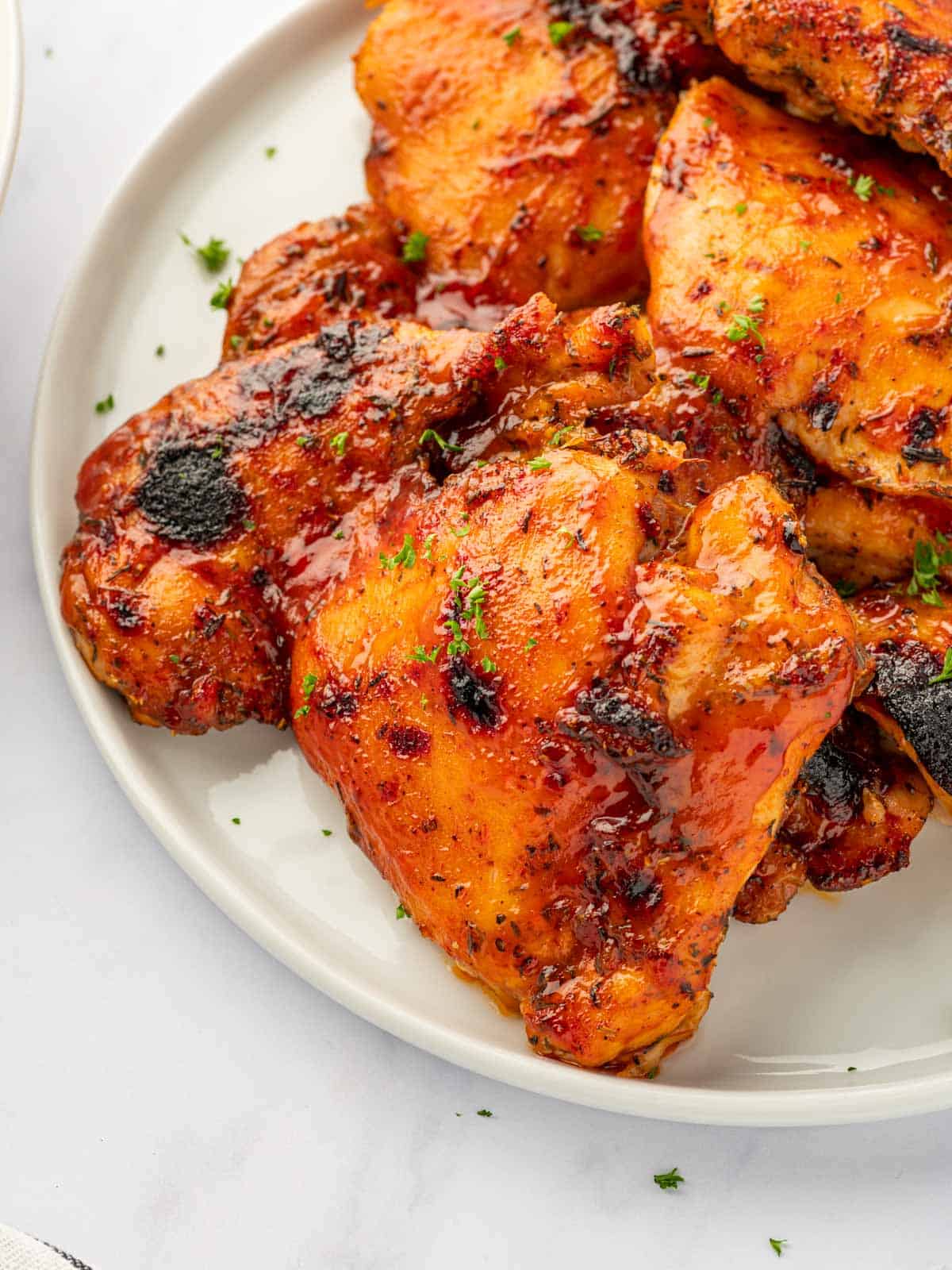 Closeup of baked barbecue chicken thighs on a plate.