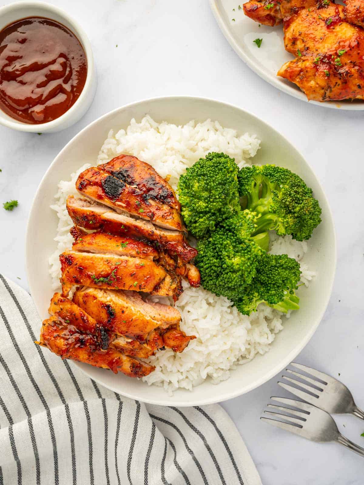 Chicken thighs on a plate with broccoli and rice.