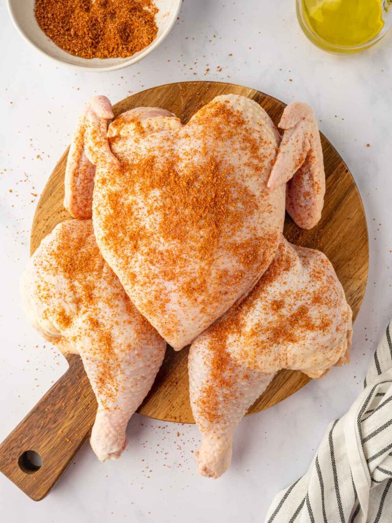 A powdered seasoning blend covers a whole raw chicken.