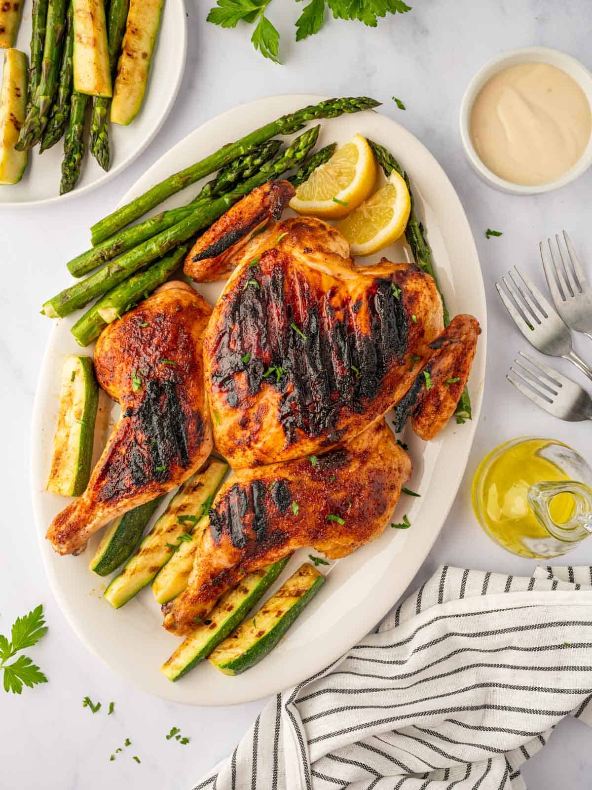 Roast chicken on a grill with roasted veggies.