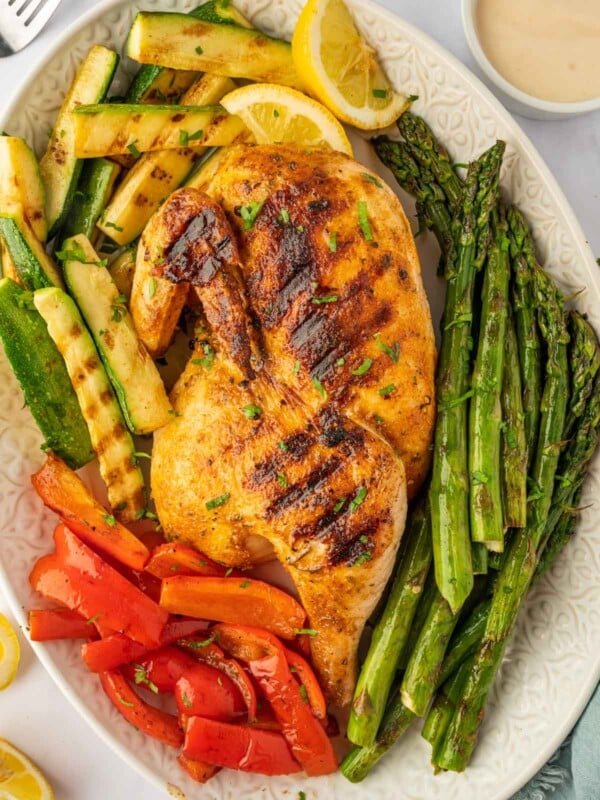 A grilled half chicken on a platter.