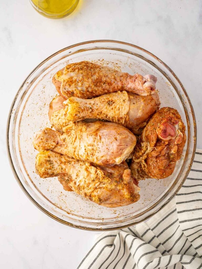 Chicken legs marinating in a bowl.