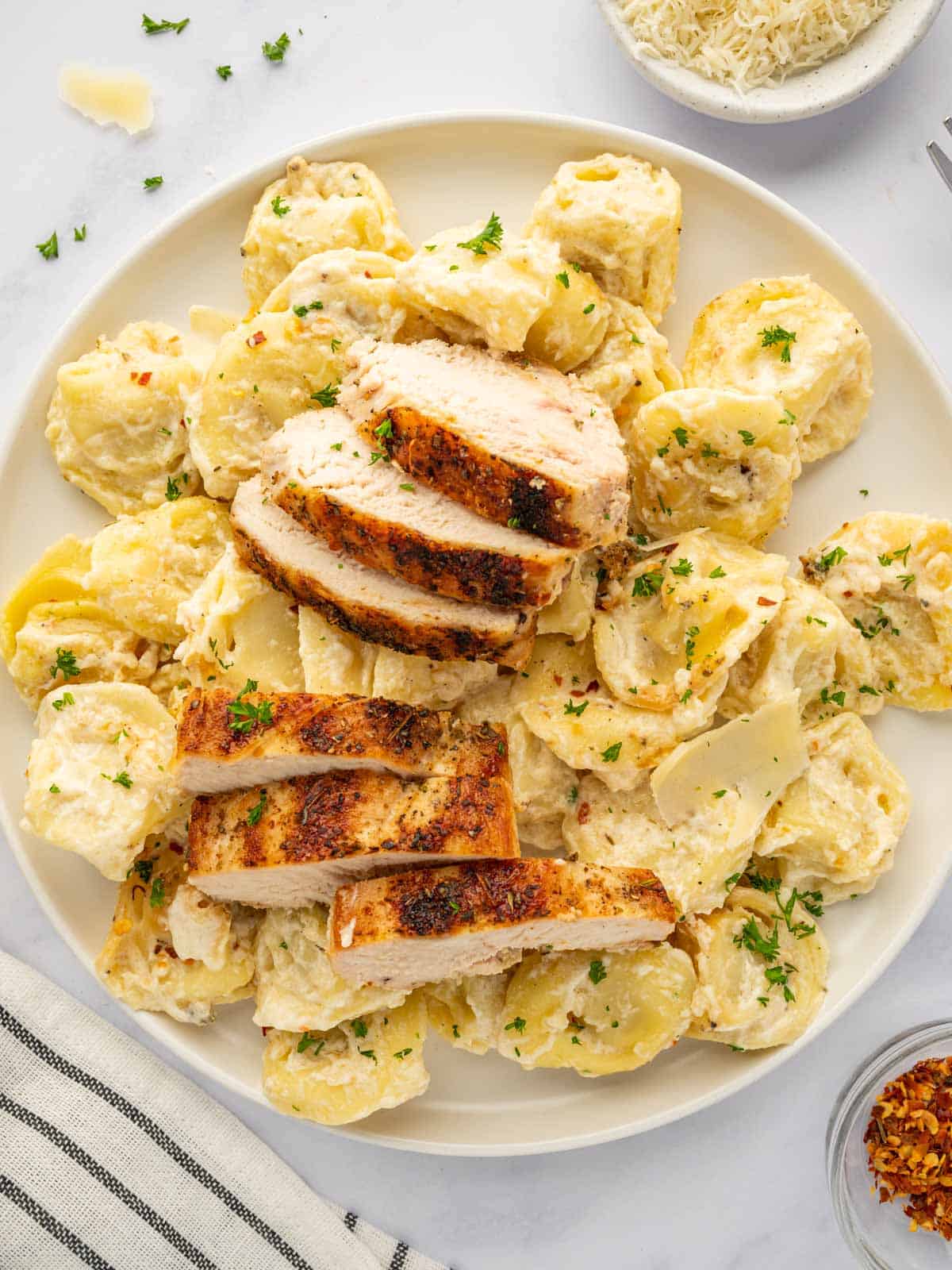 A plate with tortellini and slices of grilled chicken.