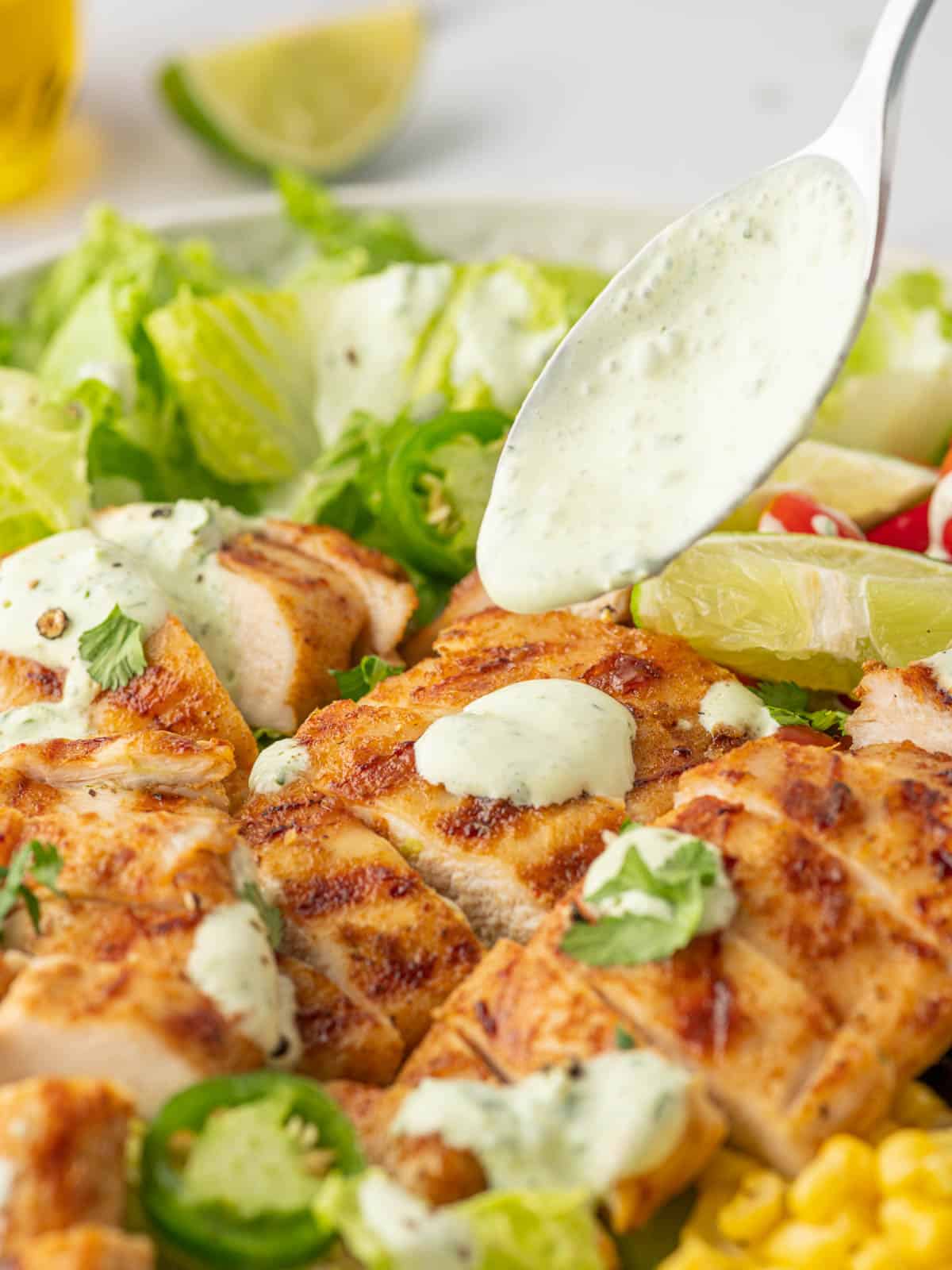 A spoon drizzles cilantro lime dressing over the salad.