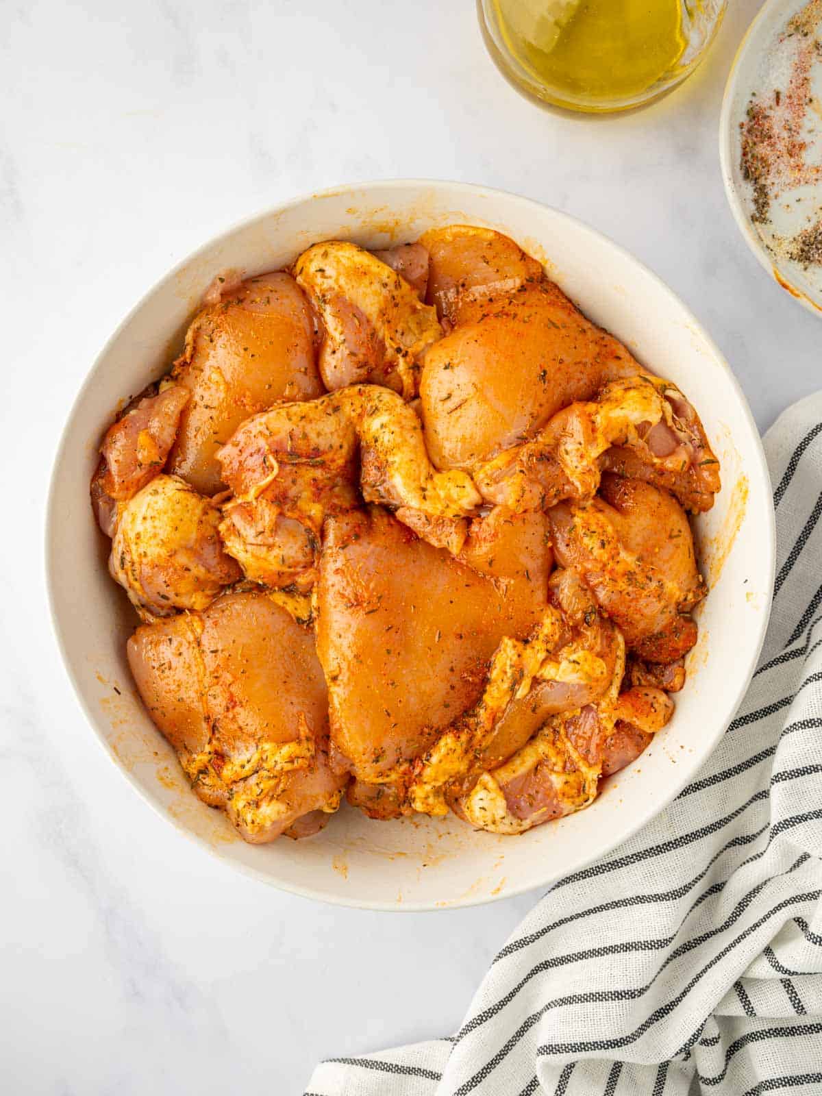 Marinating chicken thighs in seasoning and oil.