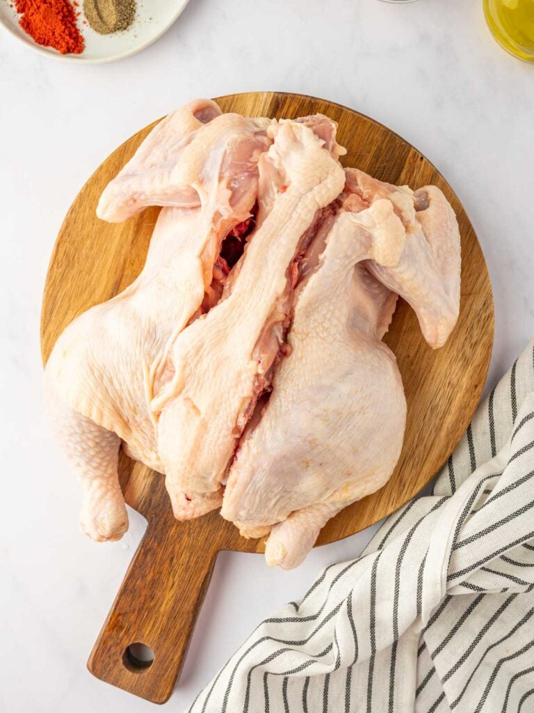 The backbone is cut to be removed from the chicken to spatchcock it.