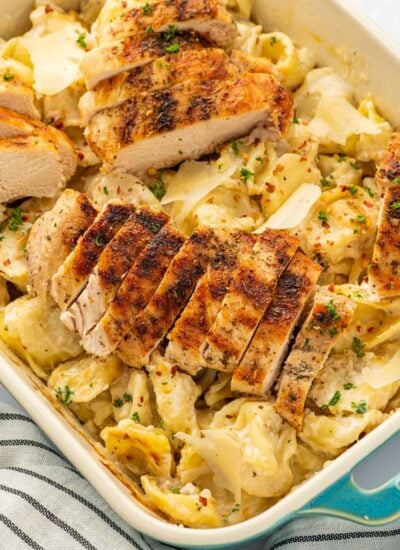 Sliced grilled chicken on top of tortellini with alfredo sauce.