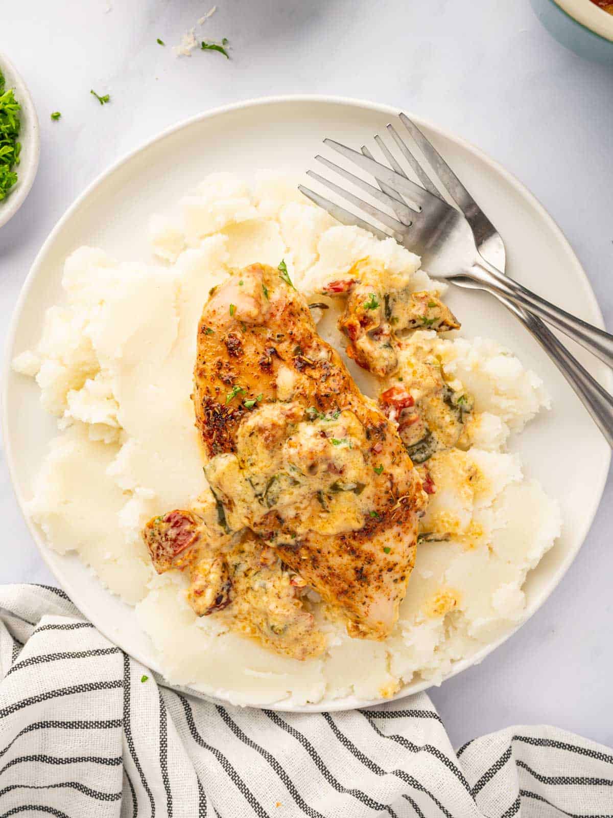 Baked tuscan chicken served over mashed potatoes.