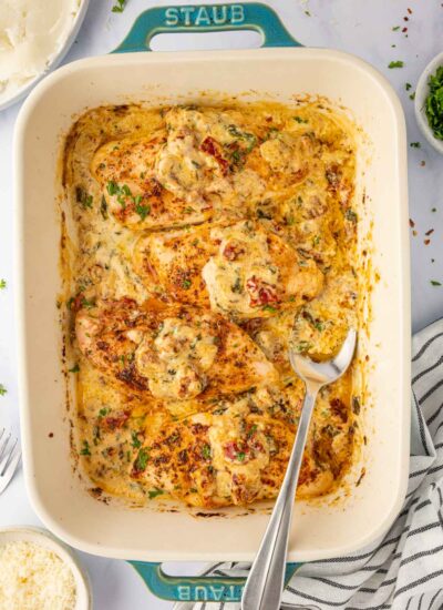 A spoon scoops tuscan sauce from the casserole dish.