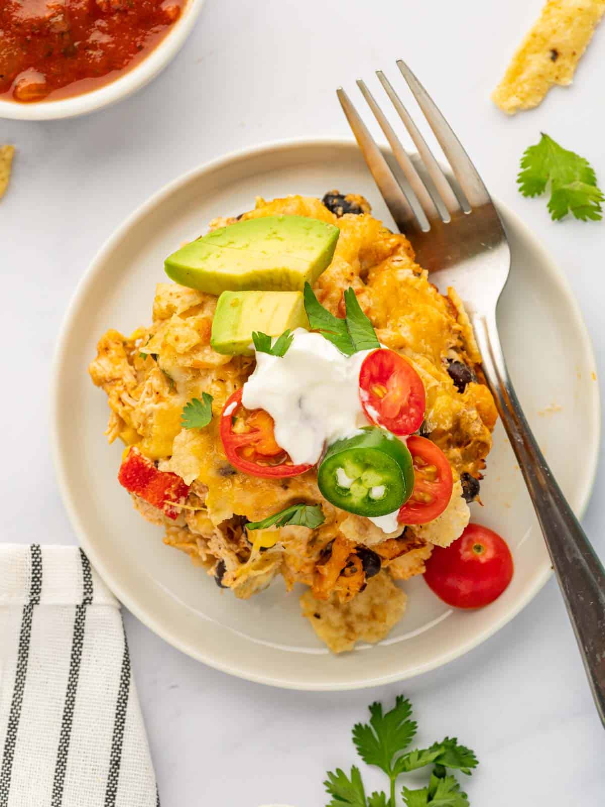 A fork rests on a plate beside a portion of chicken taco casserole.