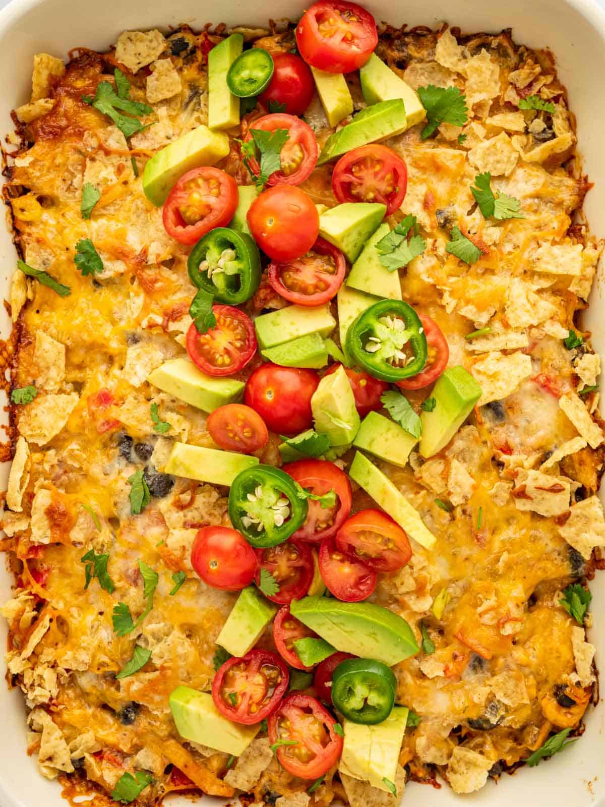 Top the baked casserole with fresh tomatoes, jalapeno and avocade.