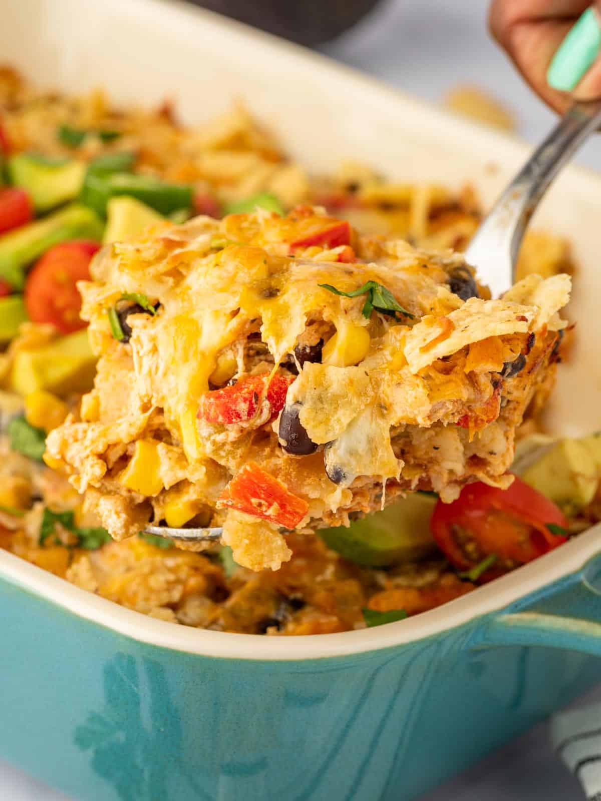 A spoon scoops out a serving of chicken Mexican casserole.