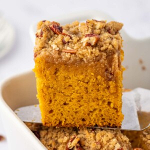 A square of pumpkin cake is lifted from a baking dish.