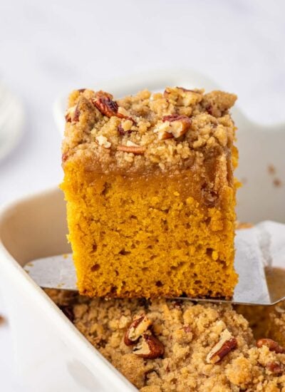 A square of pumpkin cake is lifted from a baking dish.