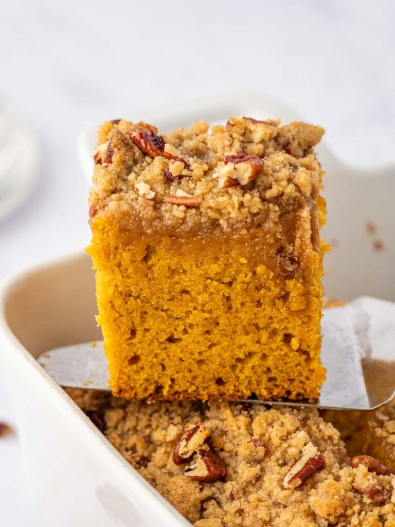 A square of pumpkin cake is lifted from a baking dish.