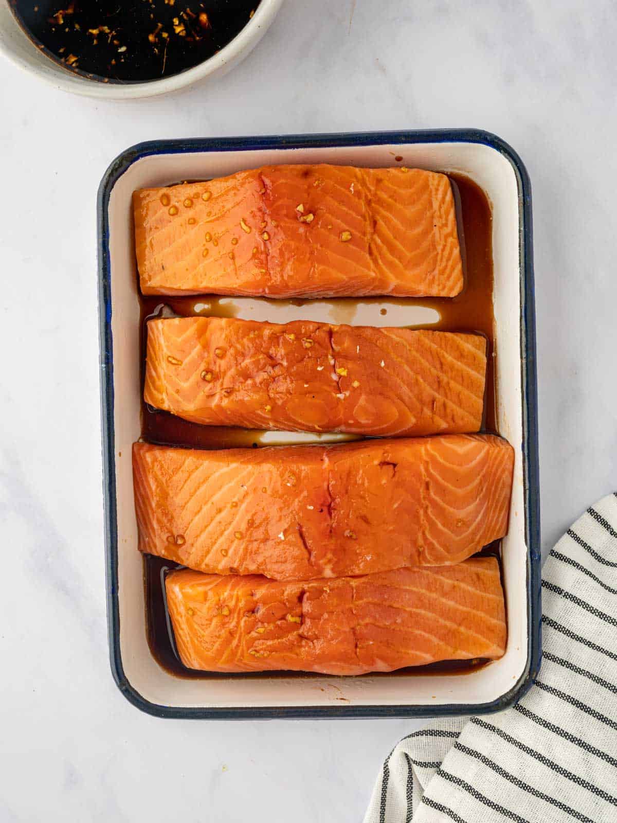 Salmon is marinated in a dish with teriyaki sauce.