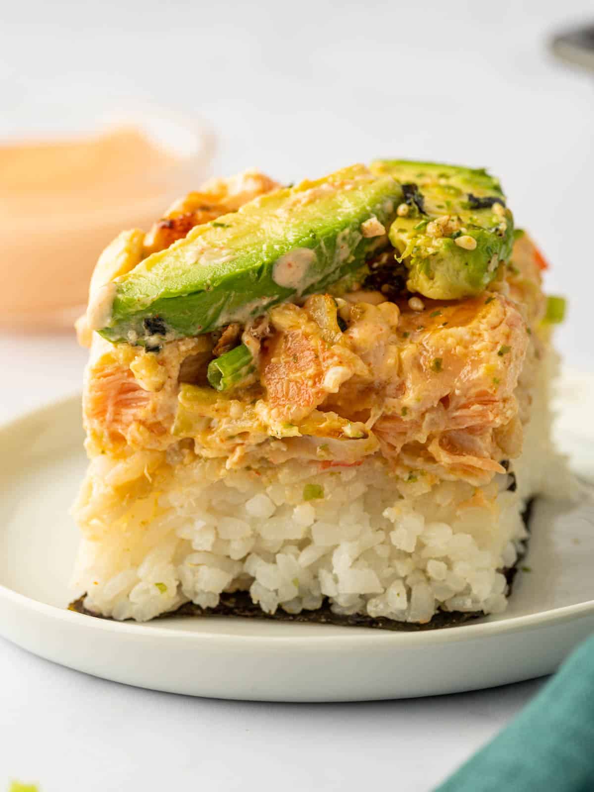 A piece of baked salmon sushi roll on a plate.