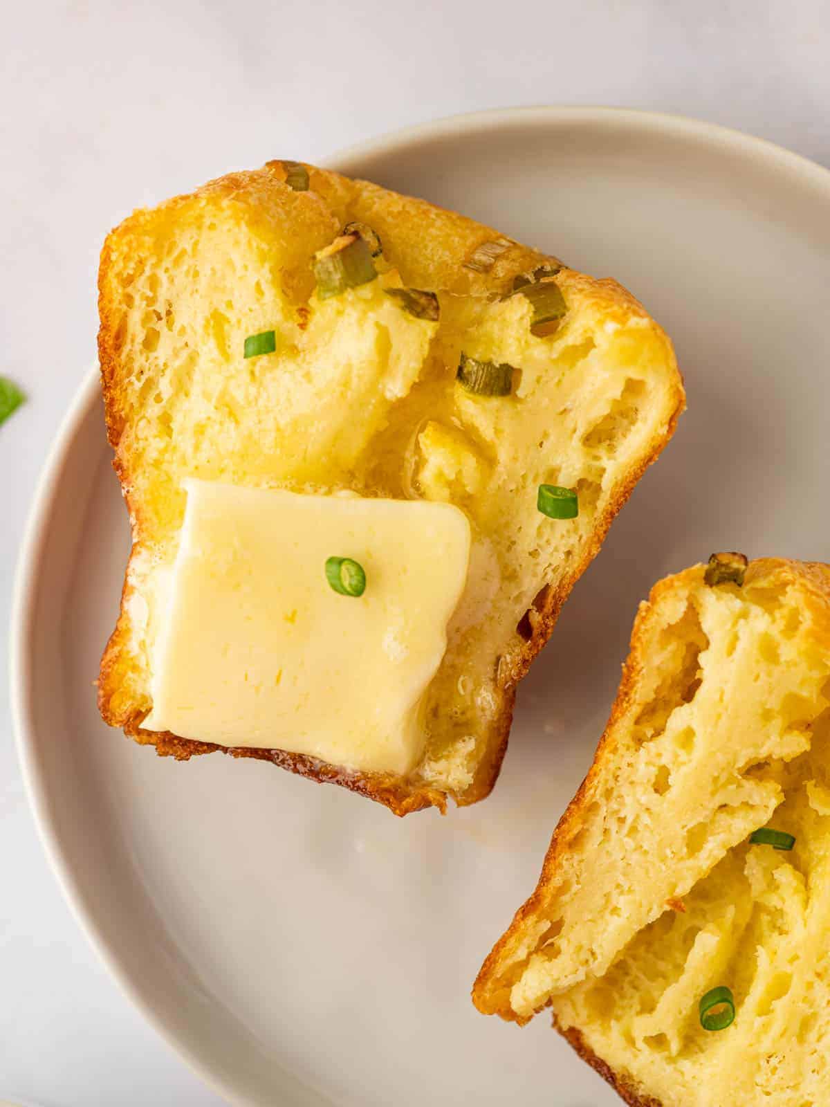 Cheesy popovers sliced open and served with butter and green onions.