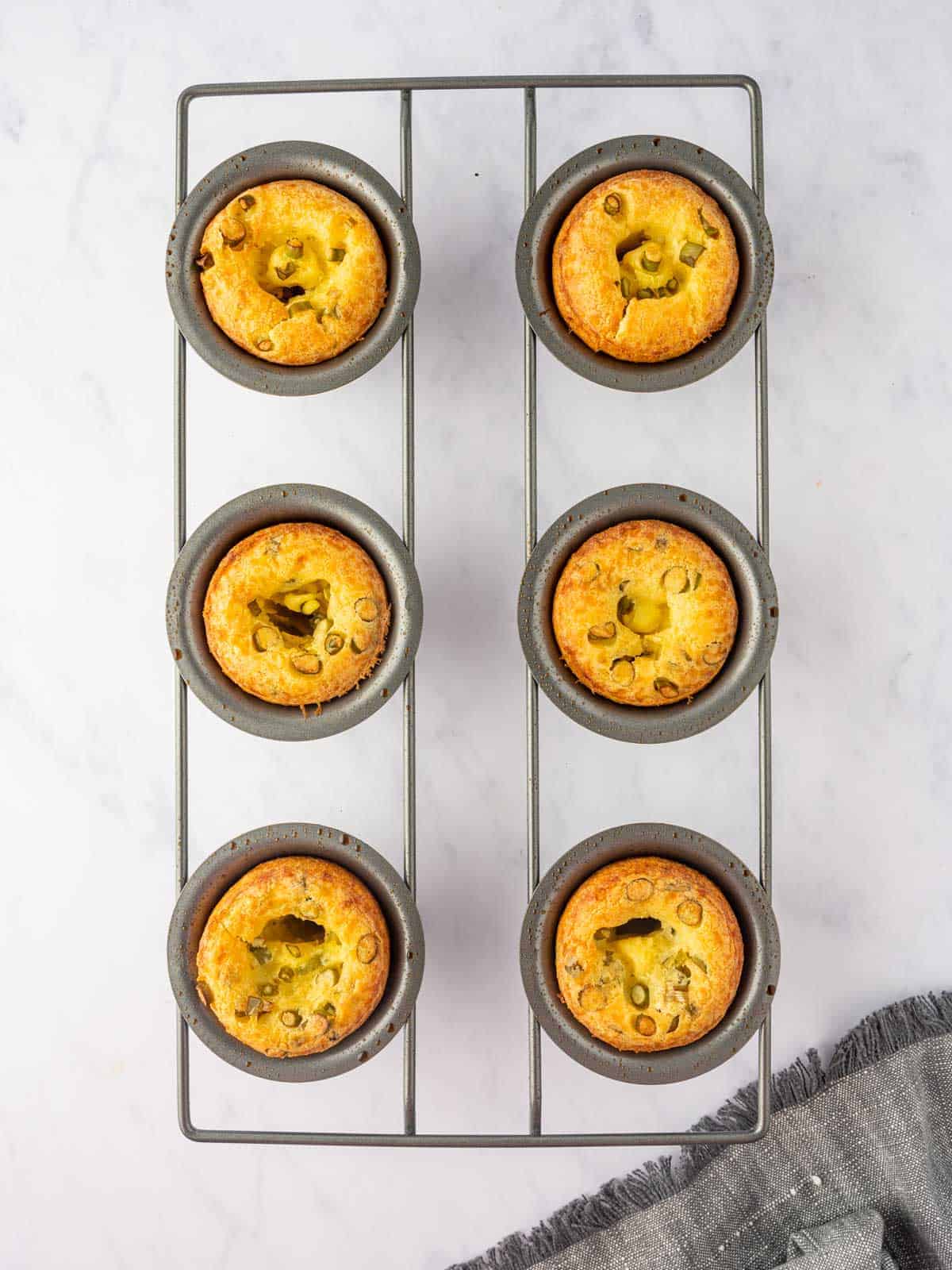 Baked cheese popovers cooling in the pan on a wire rack.