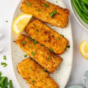 air fried mahi mahi fish fillet in a platter with lemon slices.