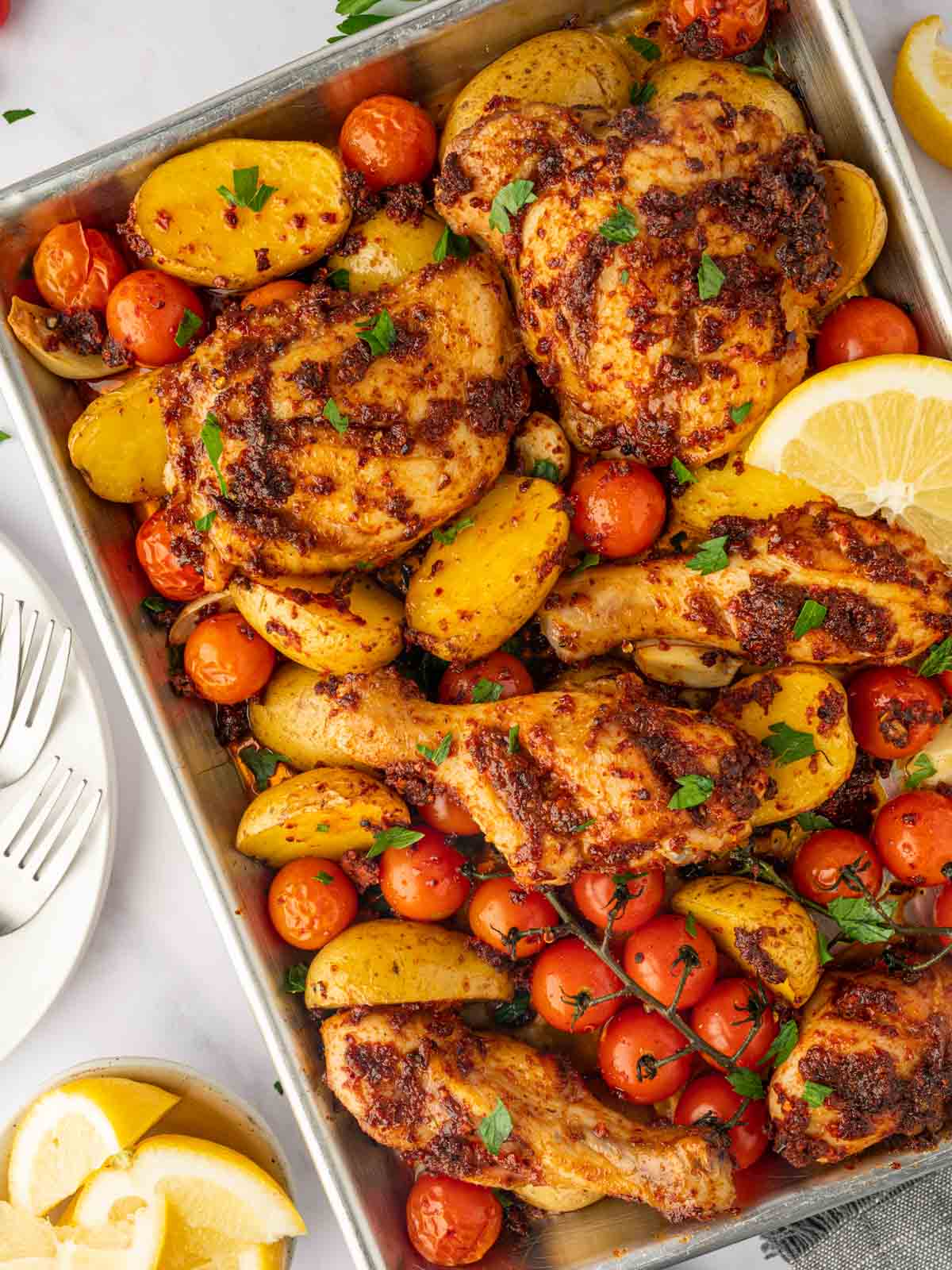 Harissa chicken traybake garnished with lemon.