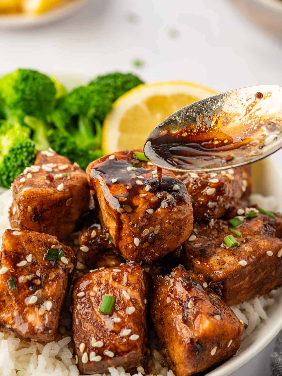 A spoon drizzles teriyaki sauce over salmon.