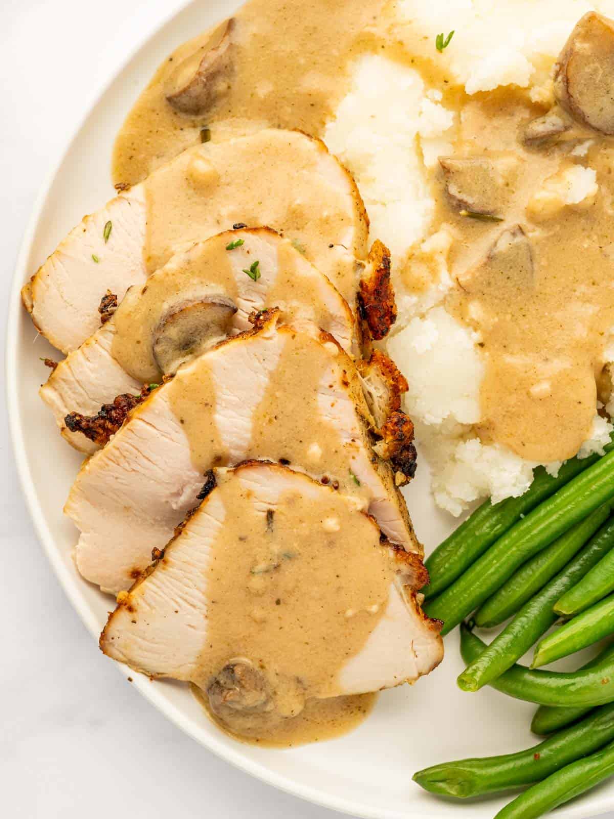 Slices of turkey breast are topped with gravy.