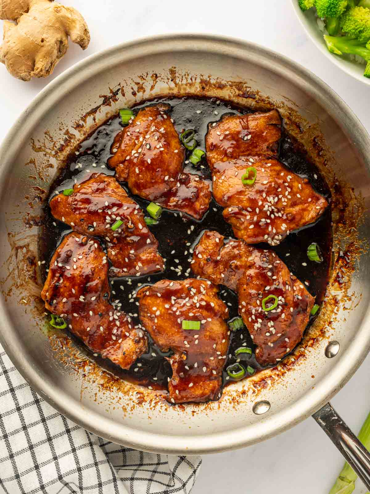 Teriyaki chicken garnished with green onions in a skillet.