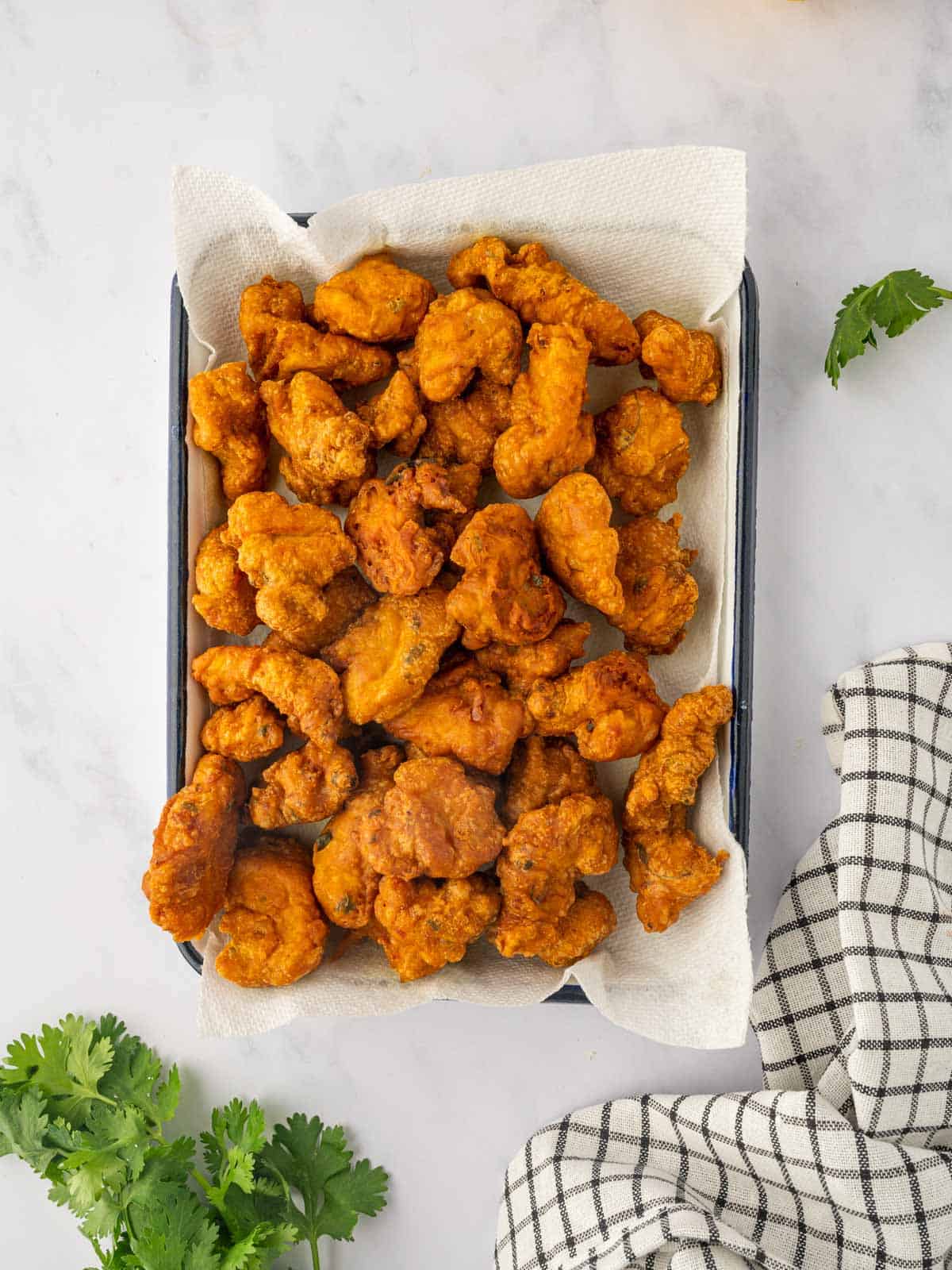 Fried chicken bites are draining on paper towels.