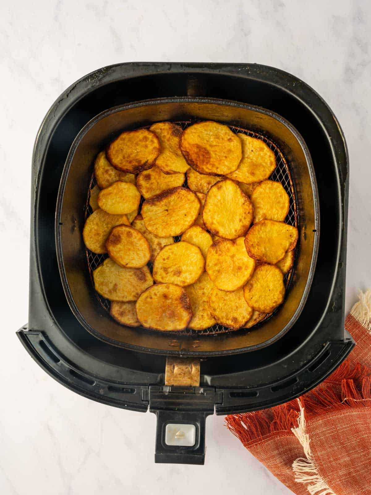 Golden, crispy potatoes in an air fryer basket.