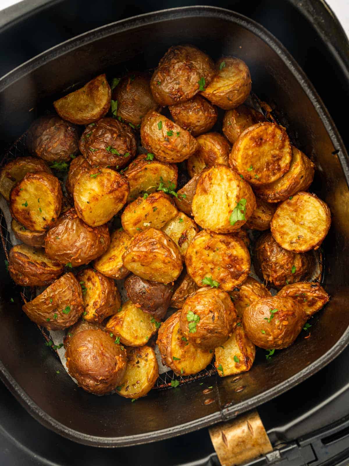 Close up of air fried red potatoes in an air fryer basket.