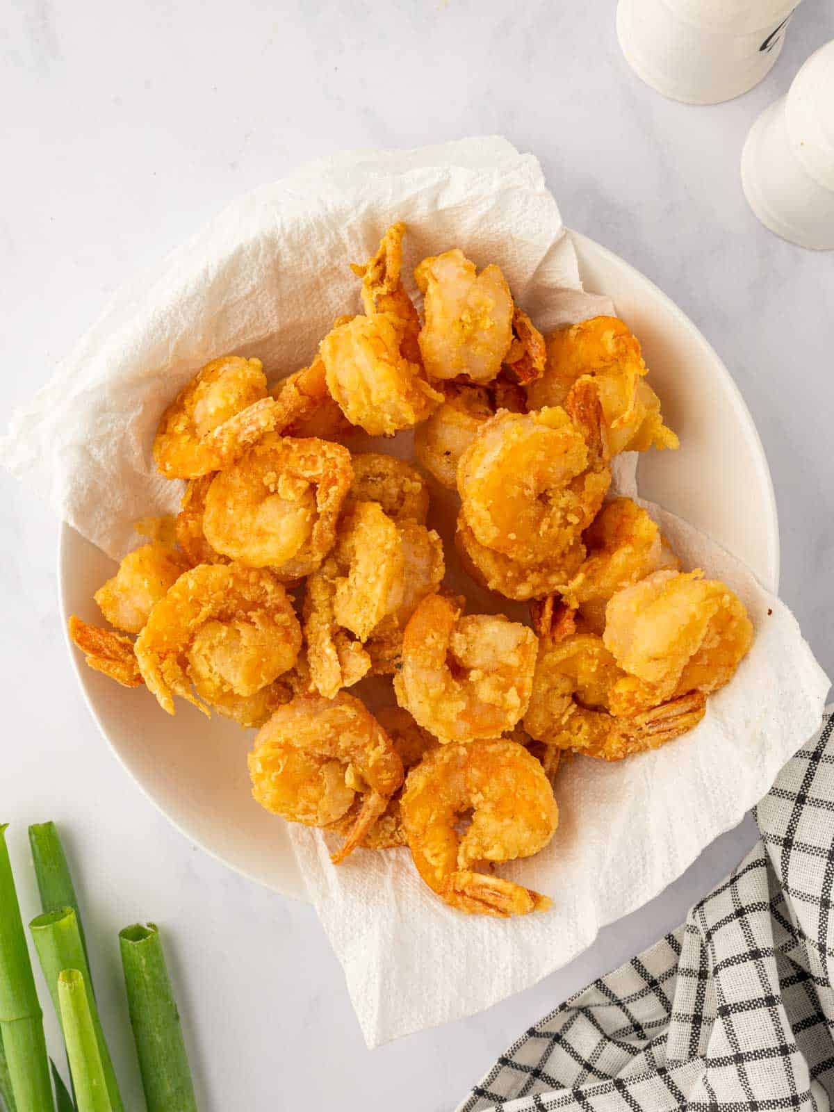 Crispy fried shrimp drains on paper towels before making salt and pepper shrimp.