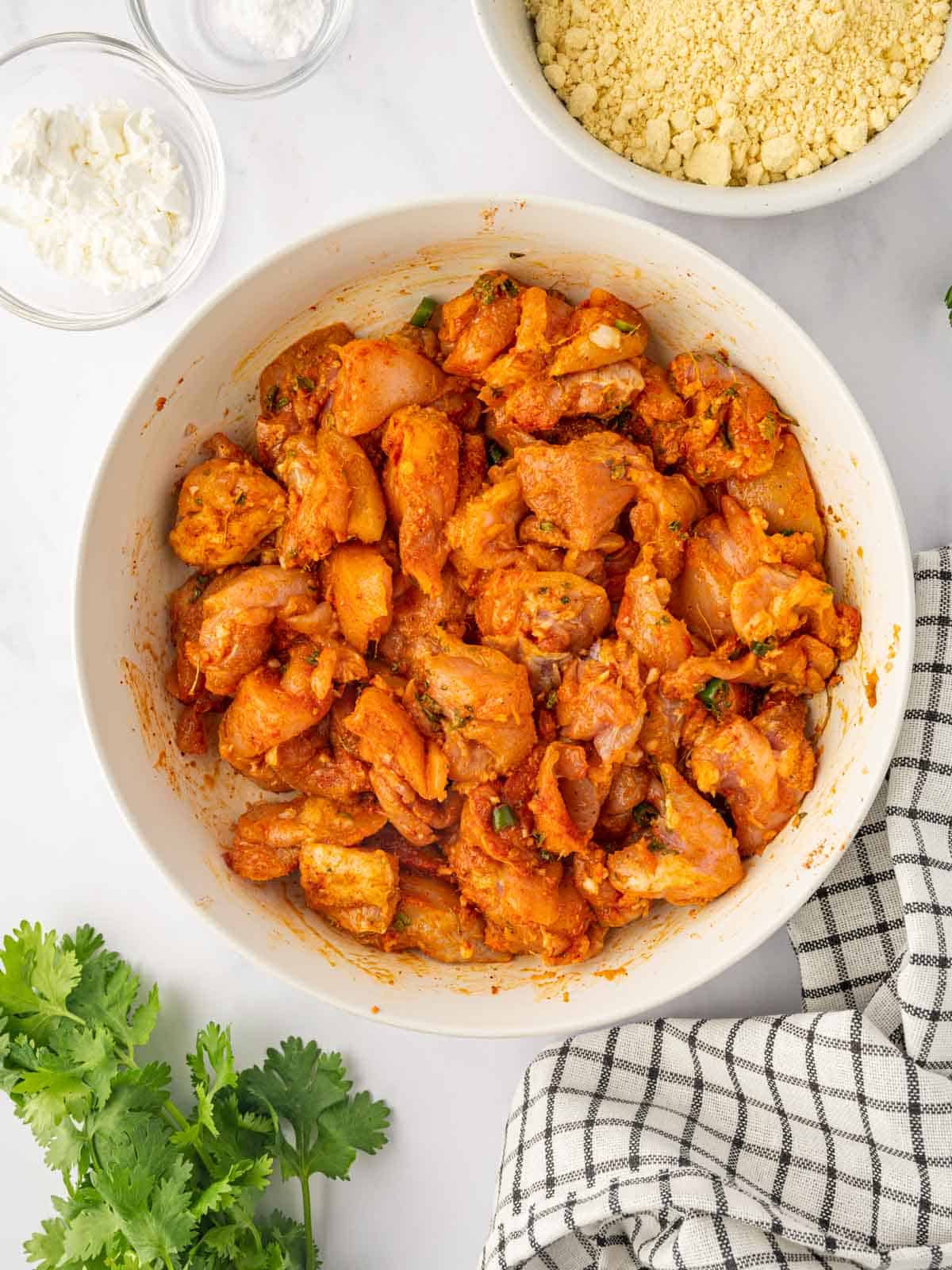 Chicken is marinated in a spicy seasoning blend in a bowl.
