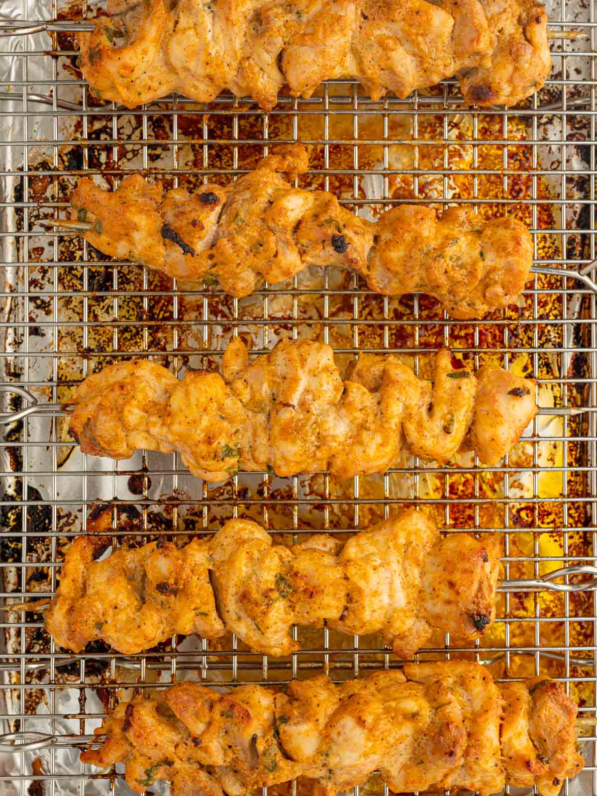 Baking chicken skewers on a tray.