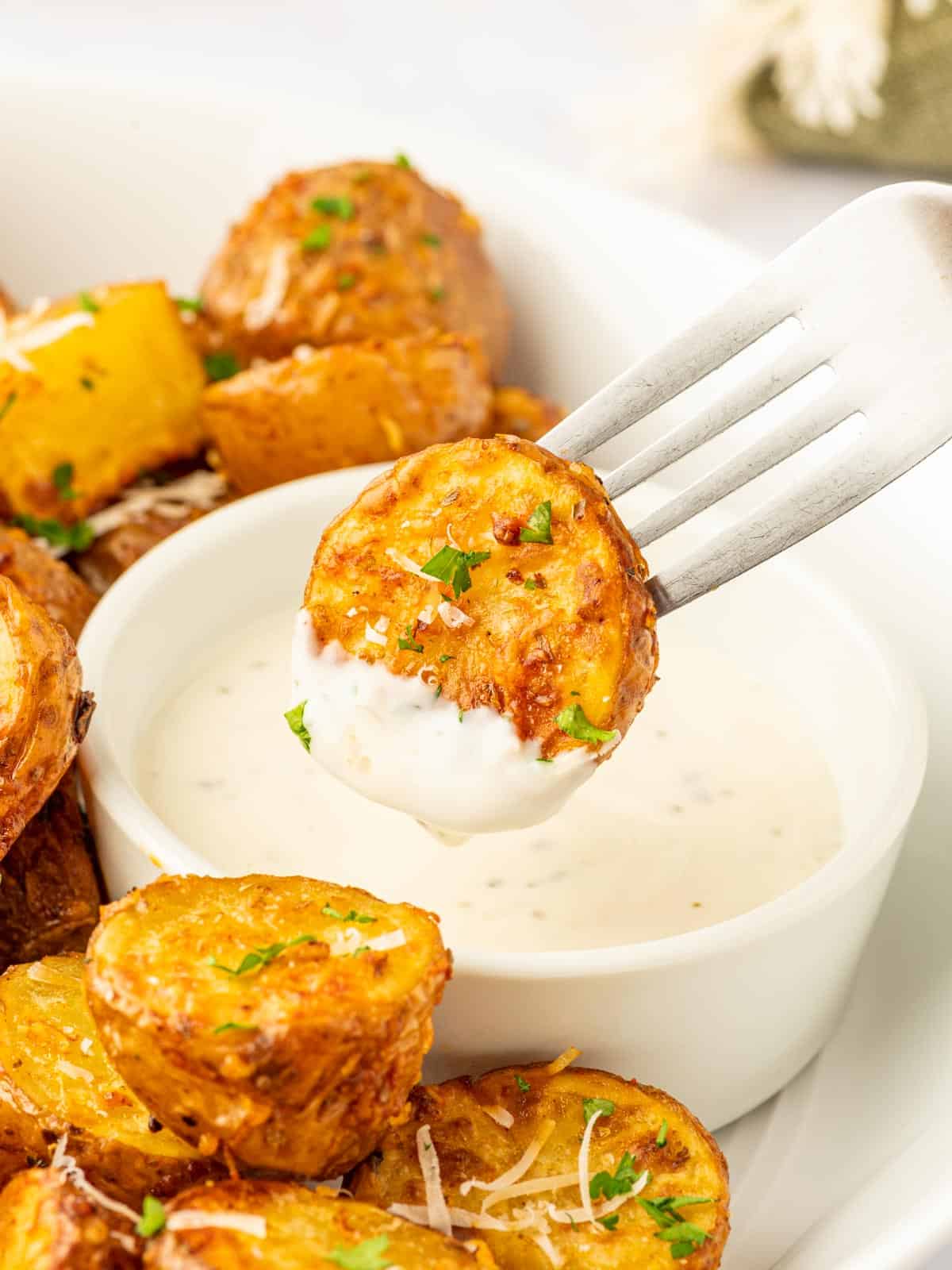A fork dips a crispy half potato into dressing.